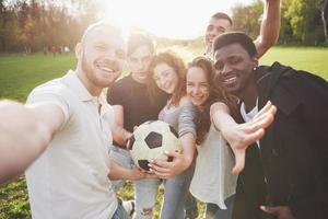 A group of friends in casual outfit do sephi on the soccer field. People have fun and have fun. Active rest and scenic sunset photo