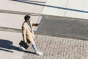 Businessman walking outdoors with briefcase, cell phone and earphones photo