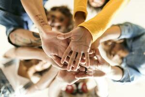 Group of happy friends huddling and stacking hands photo